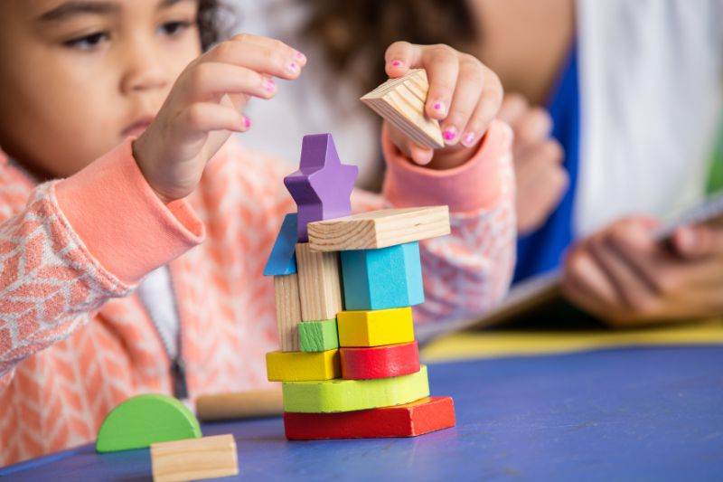 Spielendes Kind Kind baut einen Turm mit Holzklötzchen