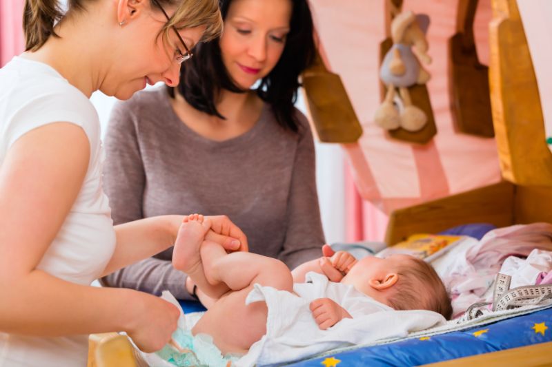 Hebamme mit Mutter und Baby Eine Hebamme leitet eine Mutter bei der Pflege des Babys an.